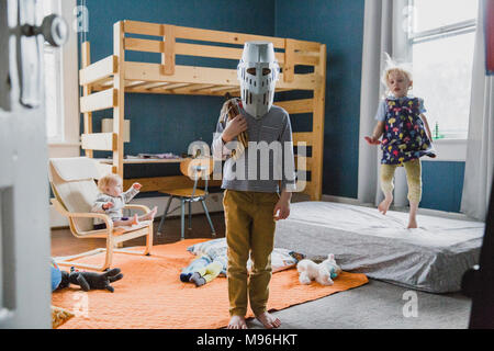 Boy with knight's helmet standing in bedroom Stock Photo