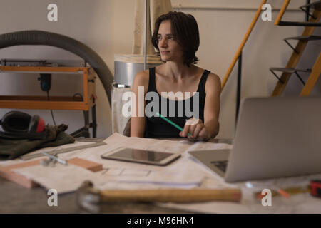 Female welder relaxing at desk in workshop Stock Photo