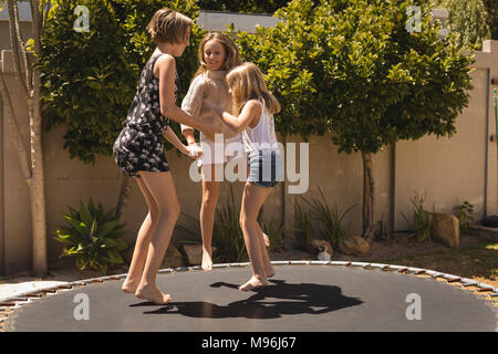 Siblings jumping on trampoline in the garden Stock Photo