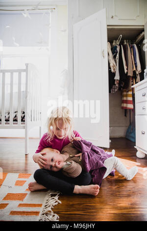 Girl with baby laying on her lap Stock Photo