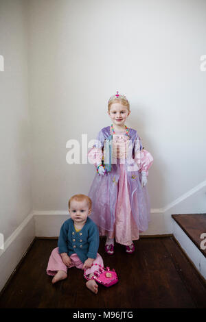 Girl in princess costume next to baby on floor Stock Photo