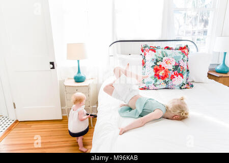 Girl laying on bed with baby next to her Stock Photo
