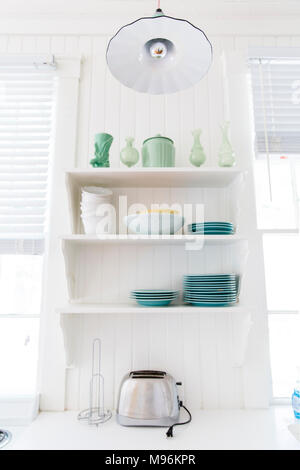 Kitchen shelves with plates, bowls and toaster Stock Photo