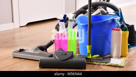 Vacuum cleaner and variety of detergent bottles and chemical cleaning supplies on the floor Stock Photo