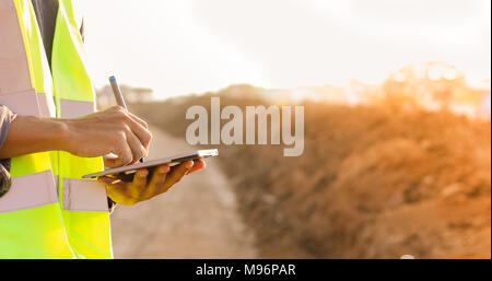 Asian engineer with hardhat using  tablet pc computer inspecting and working at construction site Stock Photo