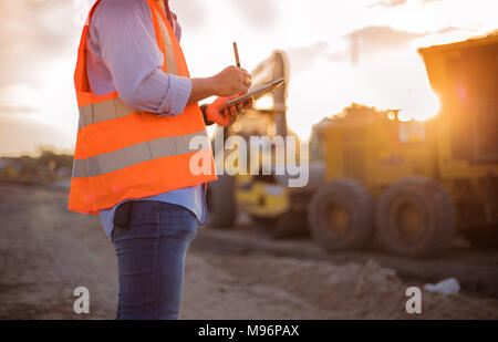 Asian engineer with hardhat using  tablet pc computer inspecting and working at construction site Stock Photo
