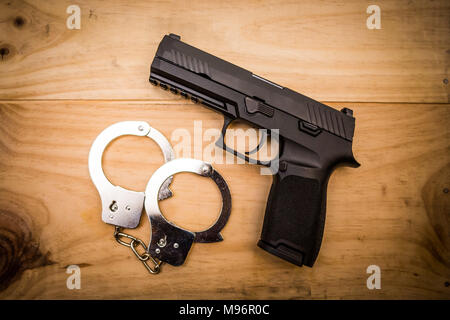 Hand gun with hand cuffs on wooden surface concept Stock Photo