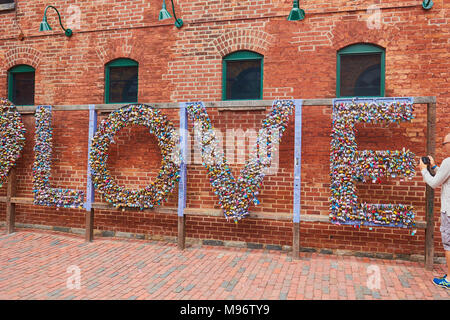 Male tourist taking photograph of the word Love made out of locks, Distillery District, Toronto, Ontario, Canada. Stock Photo
