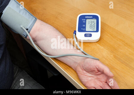 https://l450v.alamy.com/450v/m96wkx/man-using-an-omron-blood-pressure-monitor-the-check-is-achieved-through-wrapping-the-cuff-attached-to-the-machine-around-their-arm-m96wkx.jpg