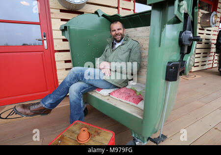 23 March 2018, Germany, Roevershagen: Robert Dahl, manager of the Karls Erlebnis-Dorf (lit. Karl's Adventure Village), sits on a garbage container which was upcycled into a seating furniture during a press event prior to the opening of the upcycling hotel 'Alles Paletti' (lit. everyhting is all right). The hotel is meant to only consist out of upcycled materials. Photo: Bernd Wüstneck/dpa Stock Photo
