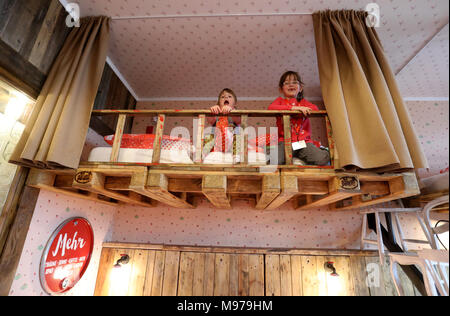 23 March 2018, Germany, Roevershagen: Marie (L-R) and Melina sit on a bunk bed during a press event prior to the opening of the upcycling hotel 'Alles Paletti' (lit. everyhting is all right) at the Karls Erlebnis-Dorf (lit. Karl's Adventure Village). The hotel is meant to only consist out of upcycled materials. Photo: Bernd Wüstneck/dpa Stock Photo