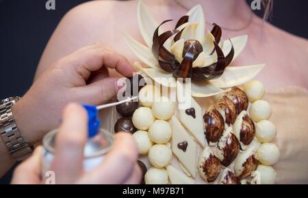 22 March 2018, Germany, Dresden: A master confectioner works on the chocolate dress 'SchoCouture'. The dress made of tulle and silk consists of altogether 160 pralines. The European Days of Arts and Craft are opened with the live performance on the same day. They take place from 23 to 25 March 2018 and run under the motto 'Kunsthandwerk zeigen - gemeinsam gestalten' (lit. showing arts and craft - craft together). Photo: Sebastian Kahnert/dpa/ZB Stock Photo