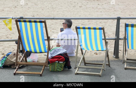 man using mobile phone on the beach at boscombe on the dorset coast Stock Photo