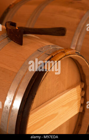 A mallets resting upon vintage wine barrels inside of a wine cellar, France Stock Photo