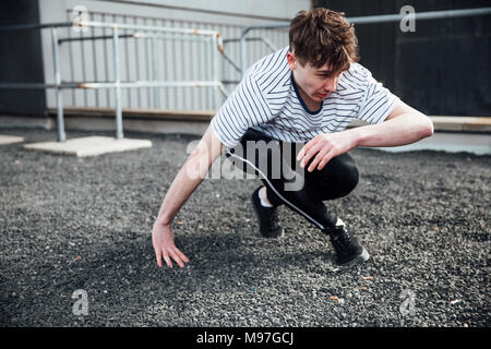 Freerunner is landing on gravel after jumping from a rooftop. Stock Photo