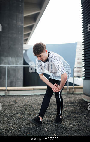 Freerunner is stretching his leg muscles on a rooftop. Stock Photo