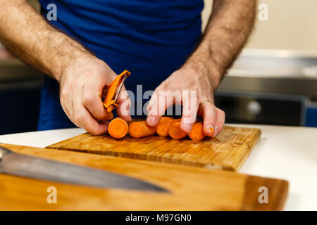 Man peeling carrots on a wooden board Stock Photo