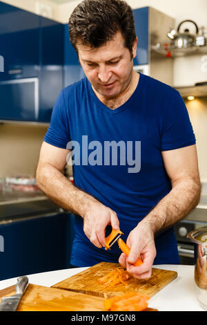 Man peeling carrots on a wooden board Stock Photo