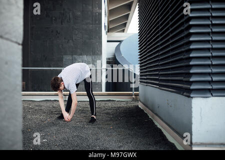 Freerunner is stretching on a rooftop. Stock Photo