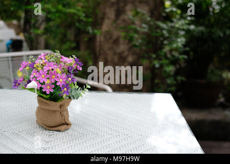 white table on terrace of house. wicker rattan chair on patio near garden at home. relaxing lifestyle concept. Stock Photo
