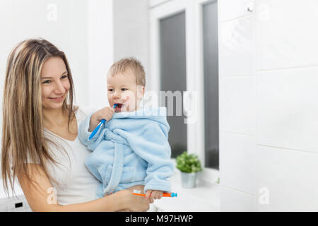 Happy mother teaching her son how to bush teeth in the bathroom Stock Photo