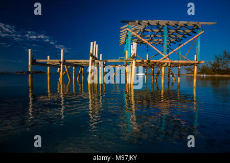 Afternoon night reflects a beautiful image of an abandoned jetty on the still shoreline of the Bahamas. Stock Photo