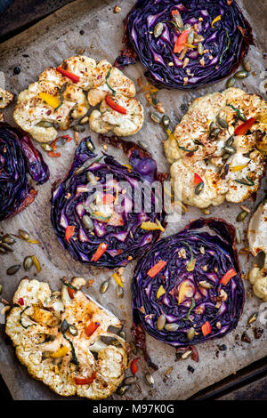 Roasted red cabbage and cauliflower steaks with seeds, chopped pepper, garlic, mint and spices. UK Stock Photo