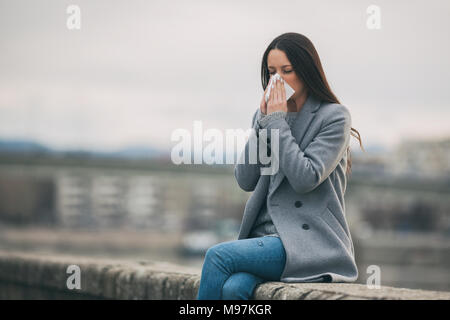 Young woman is having allergy. She is blowing her nose. Stock Photo