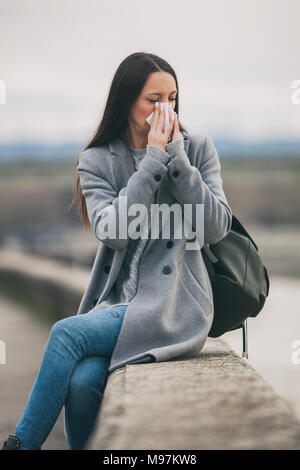 Young woman is having flu. She is blowing her nose. Stock Photo