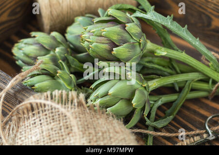 Two artichoke bouquets on kitchen table among some kitchen items. Top view. Stock Photo