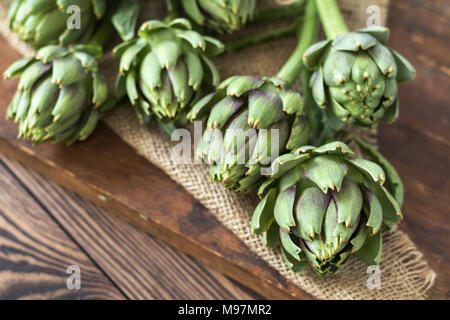 Two artichoke bouquets on kitchen table among some kitchen items. Top view. Stock Photo