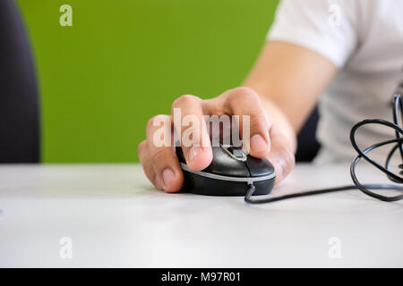 Man holding computer mouse in his hand, on the table Stock Photo