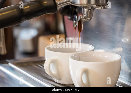 Two espresso cups getting filled in a portafilter machine Stock Photo -  Alamy