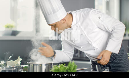 Famous Restaurant Chef Smells Steam From Saucepan. His Preparing Dishes in Modern Kitchen. Stock Photo