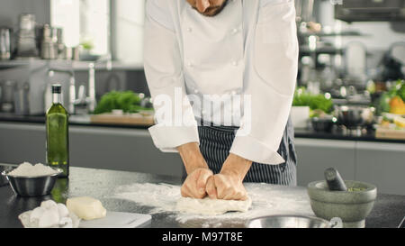 Baker Chef of Famous Restaurant Kneads the Dough in a Modern Looking Kitchen. Stock Photo