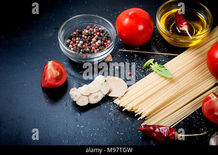 Branch ripe raw tomatoes, garlic and herbs on black background. Copy space. Stock Photo
