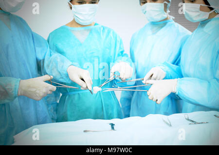Close up of medical team in masks performing operation. Focus on surgeon's hands using professional tools. Medicine, emergency help concepts Stock Photo
