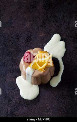 Chocolate pudding and vanilla sauce garnished with raspberry and orange Stock Photo