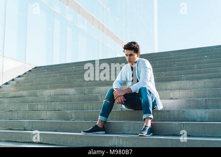 Serious young man sitting on stairs outdoors Stock Photo