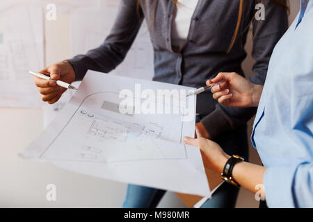 Female architects working on a project, looking at blueprint Stock Photo