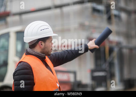 Man wearing safety vest and helmet at construction site Stock Photo