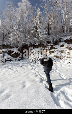 Russia, Amur Oblast, back view of man walking in snow-covered nature Stock Photo