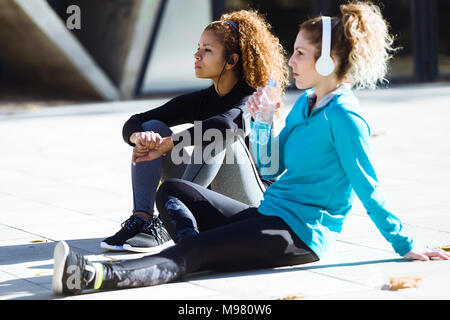 Two sportive young women having a break listening to music Stock Photo