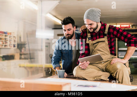 Two men with tablet looking at draft in workshop Stock Photo