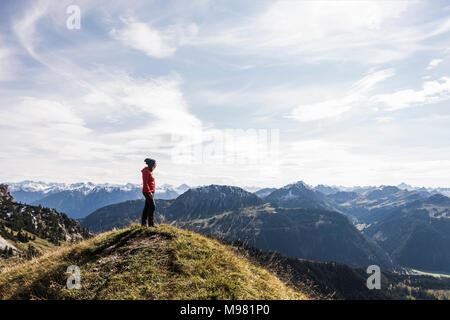 Austria, Tyrol, young woman standing in mountainscape looking at view Stock Photo