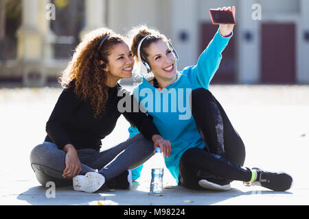 Two smiling sportive young women having a break taking a selfie Stock Photo