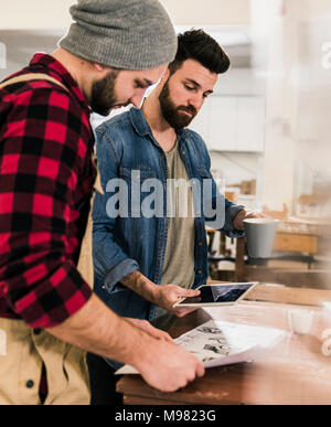 Two men with tablet looking at draft in workshop Stock Photo