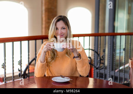 Portrait of smiling young woman in a cafe enjoying a coffee Stock Photo