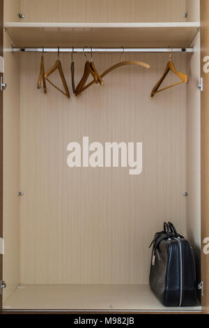 Empty coat hangers and an old-fashioned travel bag in a closet Stock Photo