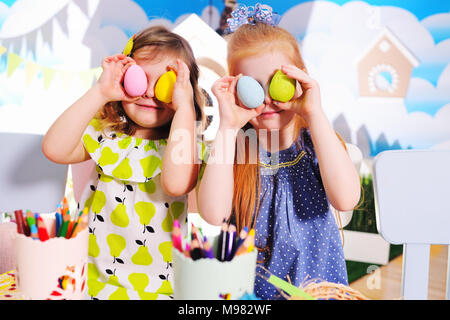 children in kindergarten paint eggs for the Easter basket at the table. Preparation for the celebration of Easter. Stock Photo